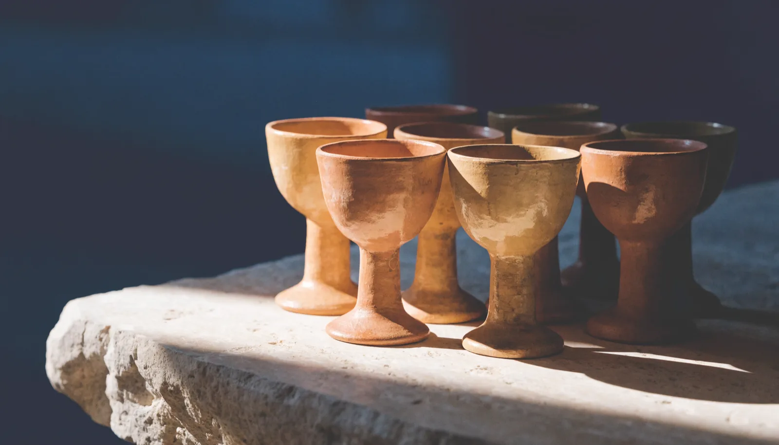 A small cluster of plain terracotta cups gathered on a stone table.